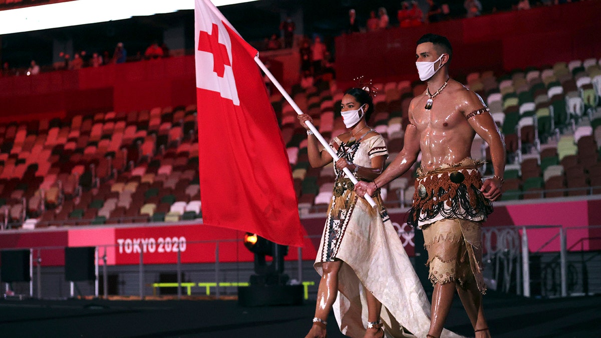 Malia Paseka and Pita Taufatofua, of Tonga, carry their country's flag during the opening ceremony in the Olympic Stadium at the 2020 Summer Olympics, Friday, July 23, 2021, in Tokyo, Japan.