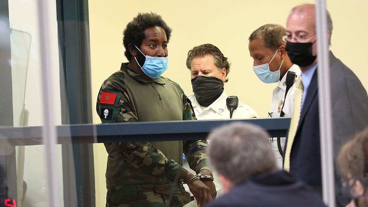 Quinn Cumberlander, left, one of 11 people charged in connection with an armed standoff along a Massachusetts highway last weekend, appears during his arraignment at Malden District Court, Tuesday, July 6, 2021, in Medford, Mass.  (Suzanne Kreiter/The Boston Globe via AP, Pool)