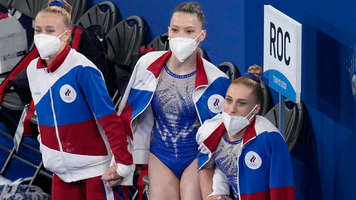 Teammates Liliia Akhaimova, right, Vladislava Urazova, center and Viktoriia Listunova watch the performance of Angelina Melnikova of the Russian Olympic Committee as she performs on the floor during the artistic gymnastics women's final at the 2020 Summer Olympics, Tuesday, July 27, 2021, in Tokyo. (AP Photo/Gregory Bull)