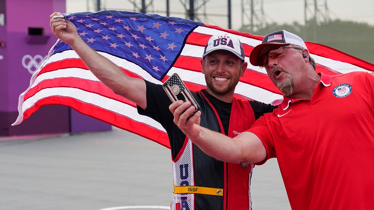 Gold medalist Vincent Hancock, of the United States, takes a selfie with his coach after the men's skeet at the Asaka Shooting Range in the 2020 Summer Olympics