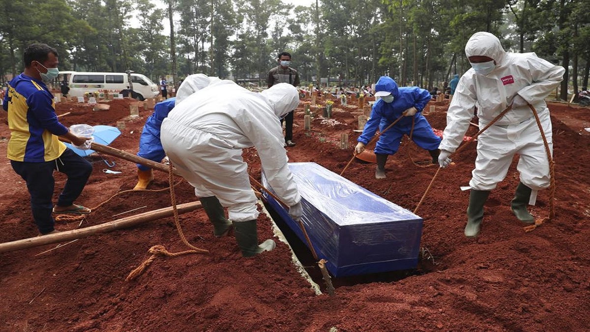 July 14, 2021: Workers in protective gear lower a coffin of a COVID-19 victim to a grave for burial at the Cipenjo Cemetery in Bogor, West Java, Indonesia. The world's fourth most populous country has been hit hard by an explosion of COVID-19 cases that have strained hospitals on the main island of Java.