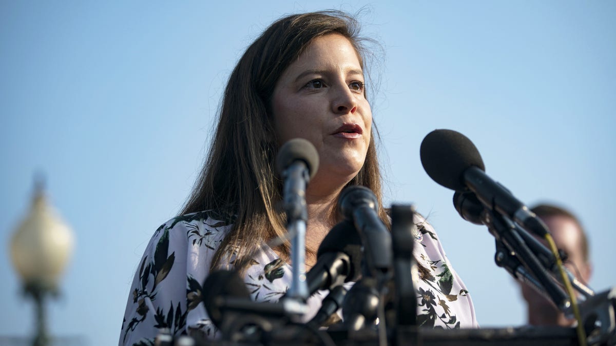 Elise Stefanik speaks into a mic during a conference outdoors