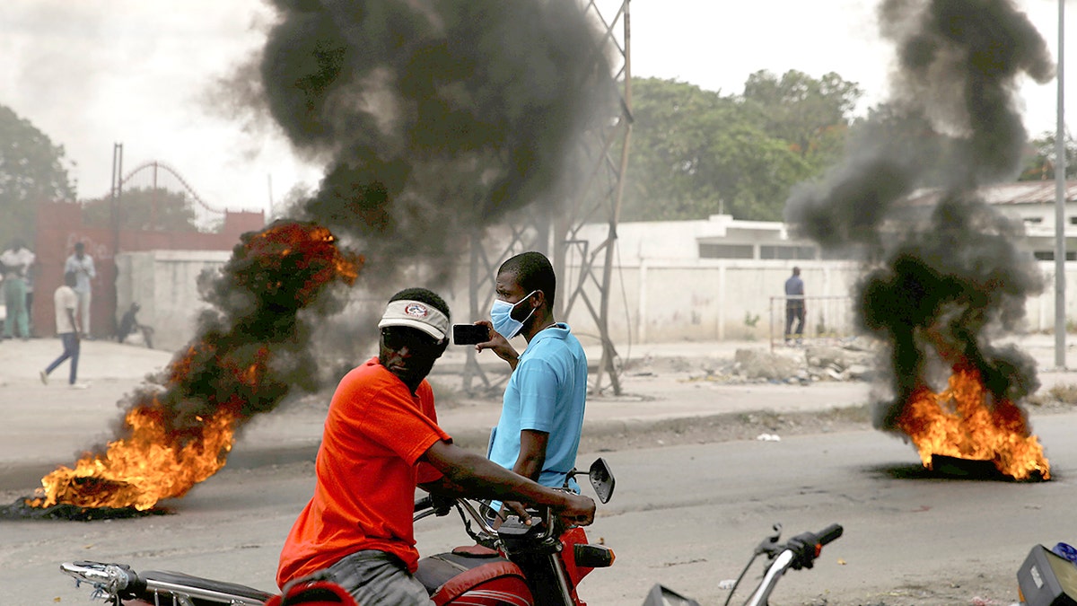 Supporters of former Senator Youri Latortue and Steven Benoit set tires on fire outside the court house in Port-au-Prince, Monday, July 12, 2021. Prosecutors have requested that high-profile politicians like Latortue and  Benoit meet officials for questioning as part of the investigation into the assassination of President Jovenel Moise. (AP Photo/Joseph Odelyn)