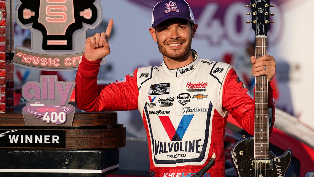 FILE - Kyle Larson celebrates with the winner's guitar and trophy after winning a NASCAR Cup Series auto race at Nashville Superspeedway in Lebanon, Tenn., in this Sunday, June 20, 2021, file photo. Rick Hendrick gave Kyle Larson a second chance in NASCAR because Hendrick Motorsports had wanted him in its lineup for years. Now that Hendrick has his man, he's locked Larson down for two more seasons with full sponsorship. Hendrick on Wednesday, July 14, told his 93 dealerships that the hottest driver in motorsports signed a contract extension through 2023 and Larson will be fully sponsored by HendrickCars.com. (AP Photo/Mark Humphrey, File)