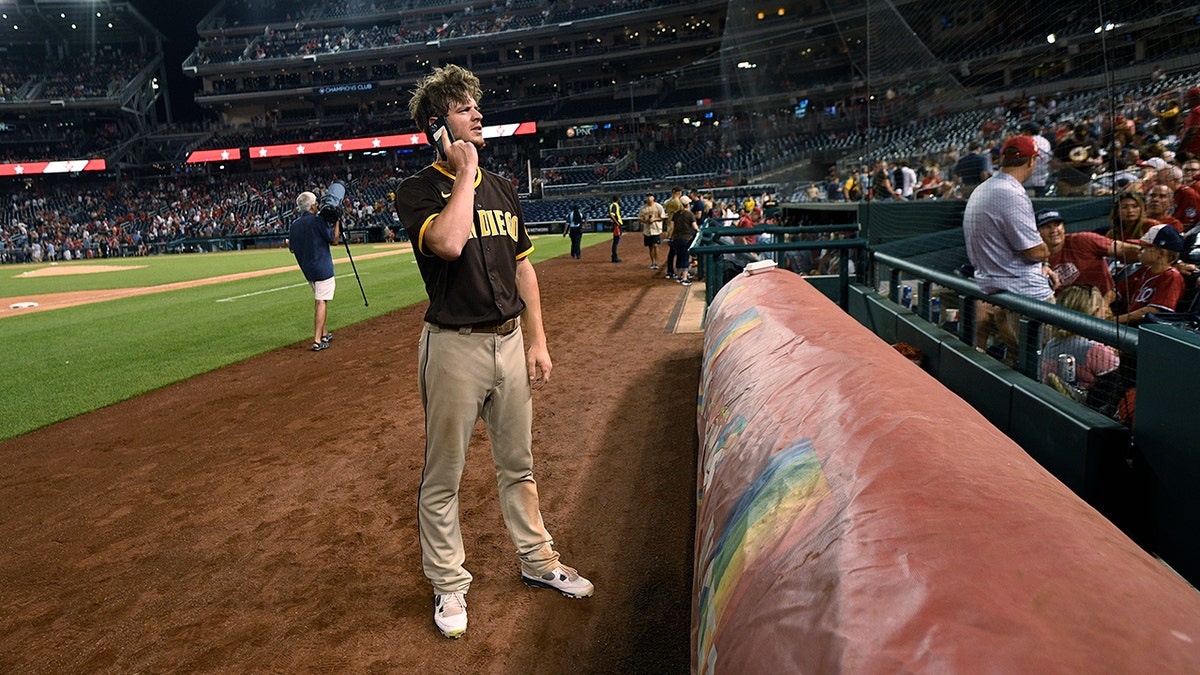 San Diego Padres player Wil Myers talks on a cell phone during a stoppage in play due to gunfire near the ballpark during the sixth inning of a baseball game between the Washington Nationals and the Padres, Saturday, July 17, 2021, in Washington. (Associated Press)