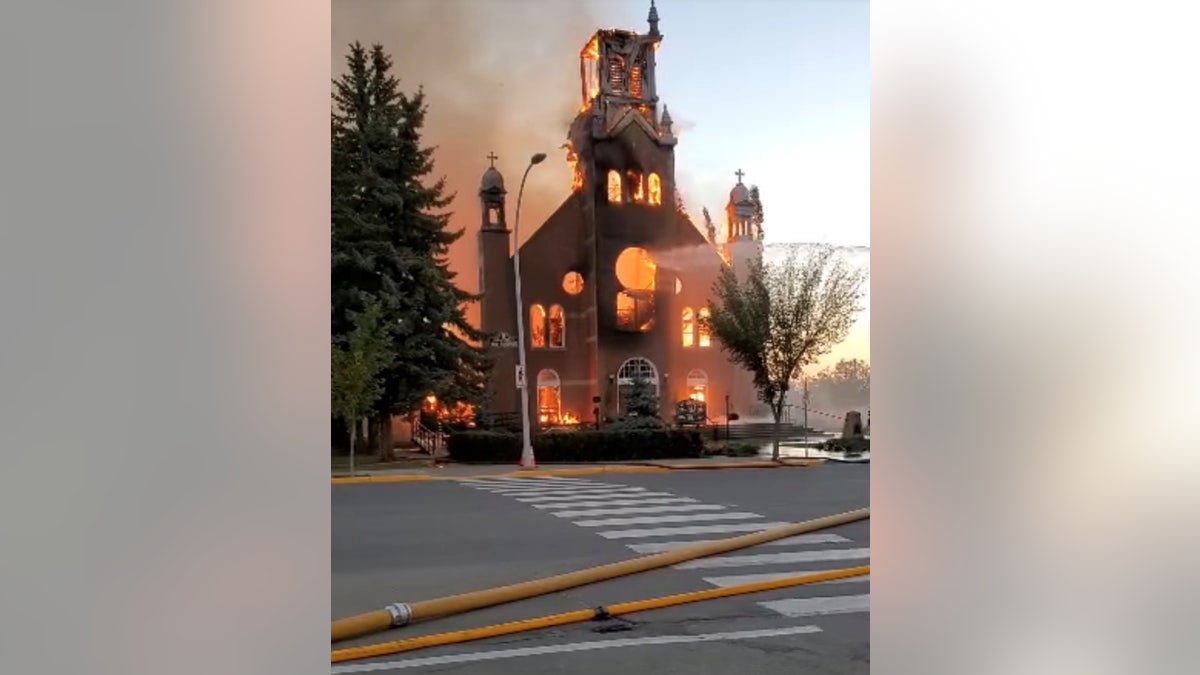 Flames engulf a Catholic church as firefighters work to extinguish the fire at St. Jean Baptiste Parish in Morinville, Alberta, Canada