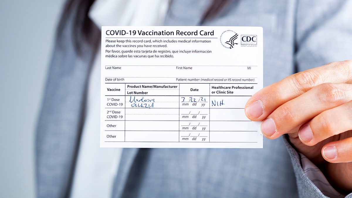 Clarksburg, MD, USA 03-29-2021: A caucasian businesswoman is showing her CDC issued COVID vaccination record card as a proof of immunization. It has the date and lot number on it.