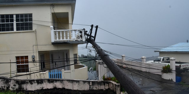 An electrical pole felled by Hurricane Elsa leans on the edge of a residential balcony, in Cedars, St. Vincent, Friday, July 2, 2021. (Associated Press)