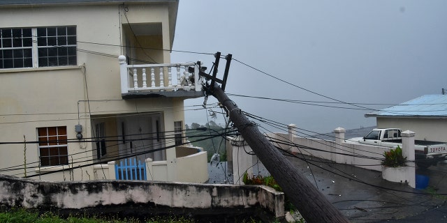 An electrical pole felled by Hurricane Elsa leans on the edge of a residential balcony, in Cedars, St. Vincent, Friday, July 2, 2021. (Associated Press)