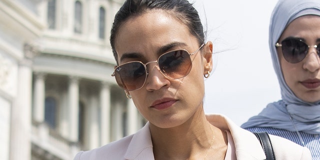 Rep. Alexandria Ocasio-Cortez, D-N.Y., talks with a reporter as she walks down the House steps 