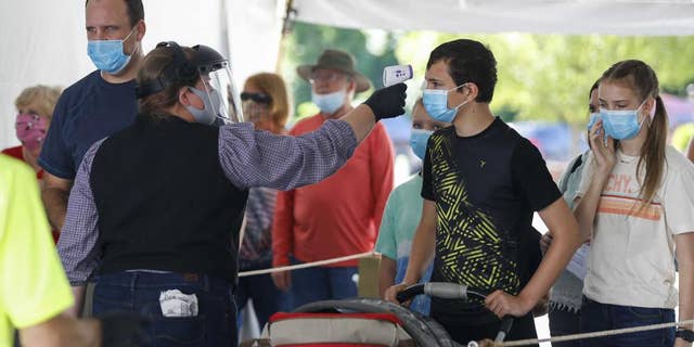 On June 13, 2021, a Silver Dollar City employee takes the temperature of guests before they are allowed to enter the park just west of Branson, Missouri (Nathan Papes / The Springfield News-Leader via AP, File )