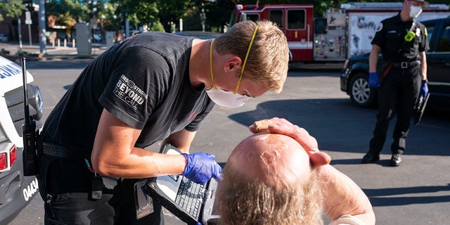 A paramedic from the Falck Northwest Ambulances treats a man exposed to heat during a heat wave, Saturday, June 26, 2021, in Salem, Ore. (AP Photo / Nathan Howard)
