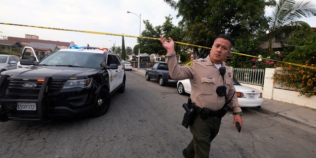 A Los Angeles County Sheriff's official works on the scene after three young children were found dead in a bedroom at a residence in East Los Angeles, Monday, June 28, 2021. (AP Photo/Ringo H.W. Chiu)