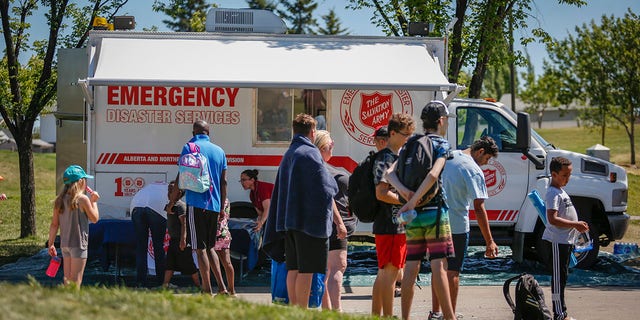 A Salvation Army EMS vehicle is setup as a cooling station as people lineup to get into a splash park while trying to beat the heat in Calgary, Alberta, 星期三, 六月 30, 2021. (Jeff McIntosh/The Canadian Press via AP)
