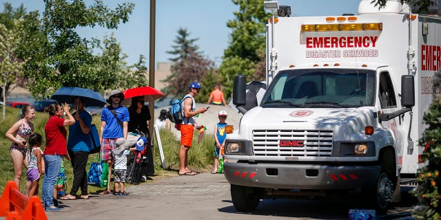A Salvation Army EMS vehicle is setup as a cooling station as people lineup to get into a splash park while trying to beat the heat in Calgary, Alberta., Wednesday, June 30, 2021.