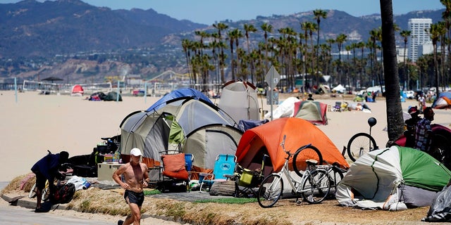 A jogger walks past a homeless encampment in the Venice Beach section of Los Angeles. A dead body was discovered on fire Tuesday morning near downtown Los Angeles.
