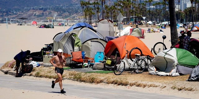 A jogger walks past a homeless encampment in Los Angeles, California.