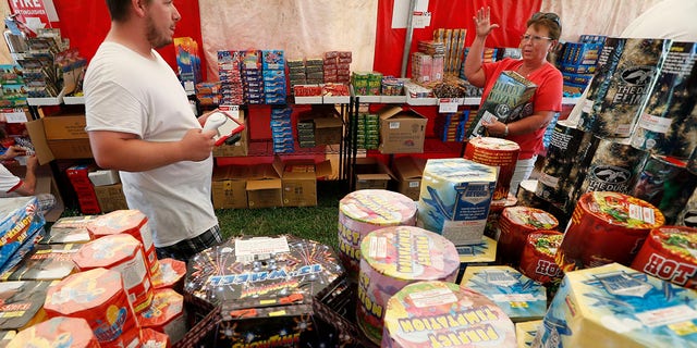 FILE - In this Thursday, June 15, 2017, file photo, Bryce Walter, of Ankeny, Iowa, talks with customer Deb Crowl, right, about fireworks for sale in a tent owned by the Iowa Fireworks Company, in Adel, Iowa. (AP Photo/Charlie Neibergall, File)