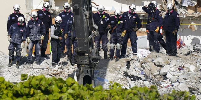 Search and rescue personnel work alongside heavy machinery atop the rubble at the Champlain Towers South condo building, where scores of people remain missing more than a week after it partially collapsed, Vrydag, Julie 2, 2021, in Surfside, Fla. Rescue efforts resumed Thursday evening after being halted for most of the day over concerns about the stability of the remaining structure.(AP Foto / Mark Humphrey)