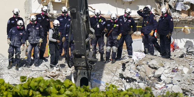Search and rescue personnel work alongside heavy machinery atop the rubble at the Champlain Towers South condo building, where scores of people remain missing more than a week after it partially collapsed, Friday, July 2, 2021, in Surfside, Fla. Rescue efforts resumed Thursday evening after being halted for most of the day over concerns about the stability of the remaining structure.(AP Photo/Mark Humphrey)
