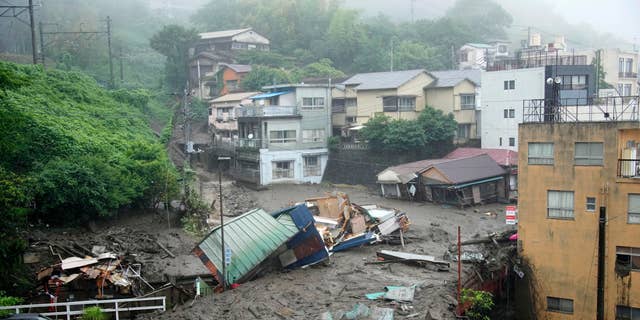 Houses are damaged by mudslide following heavy rain at Izusan district in Atami, west of Tokyo, Saturday, July 3, 2021. A powerful mudslide carrying a deluge of black water and debris crashed into rows of houses in a town west of Tokyo following heavy rains on Saturday, leaving multiple people missing, officials said.  (Naoya Osato/Kyodo News via AP)