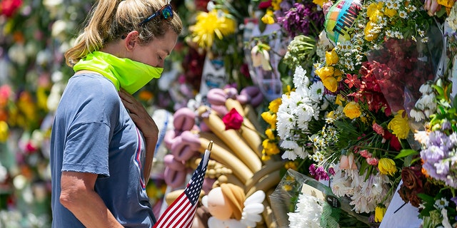 Miami Beach resident Tracey Lynne visits a makeshift memorial near the site of the collapsed Champlain Towers South Condo in Surfside, Florida, on Saturday, July 3, 2021. (Associated Press)