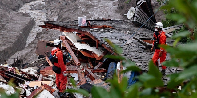 Rescuers conduct a search operation at the site of an Izusan mudslide in Atami, Shizuoka prefecture, southwest of Tokyo, Sunday, July 4, 2021. More than 1,000 soldiers, firefighters and police waded through Sunday in a giant mudslide that devastated the city seaside resort, sweeping away homes and cars. (Kyodo news via AP)