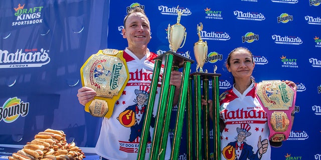 Winners Joey Chestnut and Michelle Lesco pose with their championship belts and trophies at the Nathan's Famous Fourth of July International Hot Dog-Eating Contest in Coney Island's Maimonides Park on Sunday, July 4, 2021, in Brooklyn, New York. 
