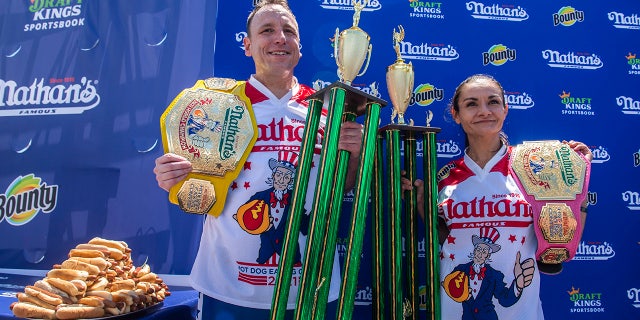 Winners Joey Chestnut and Michelle Lesco pose with their championship belts and trophies at the Nathan's Famous Fourth of July International Hot Dog-Eating Contest in Coney Island's Maimonides Park on Sunday, July 4, 2021, in Brooklyn, New York.