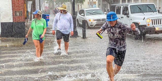 Pedestrians dash across the intersection of Greene and Duval streets as heavy winds and rain associated with Tropical Storm Elsa passes Key West, Fla., on Tuesday, July 6, 2021. (Rob O'Neal/The Key West Citizen via AP)
