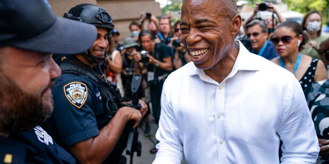 Brooklyn Borough President and a Democratic mayoral candidate Eric Adams greets NYPD officers as participants gather for a march through the financial district during a parade honoring essential workers for their efforts in getting New York City through the COVID-19 pandemic, Wednesday, July 7, 2021, in New York. The parade kicked off at Battery Park and travel up Broadway in lower Manhattan, the iconic stretch known as the Canyon of Heroes, which has hosted parades honoring world leaders, celebrities and winning sports teams. (AP Photo/John Minchillo)