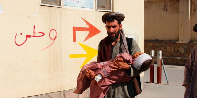 An Afghan civilian carry a wounded child to the hospital after he was injured during fighting between Taliban and government in Badghis province, northwest of Afghanistan, Wednesday, July, 7 2021.