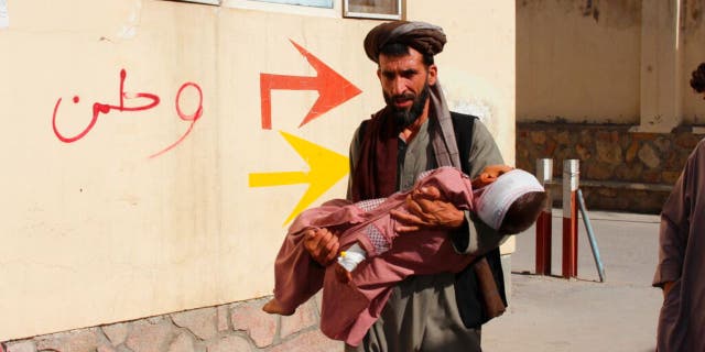 An Afghan civilian carry a wounded child to the hospital after he was injured during fighting between Taliban and government in Badghis province, northwest of Afghanistan, Wednesday, July, 7 2021.