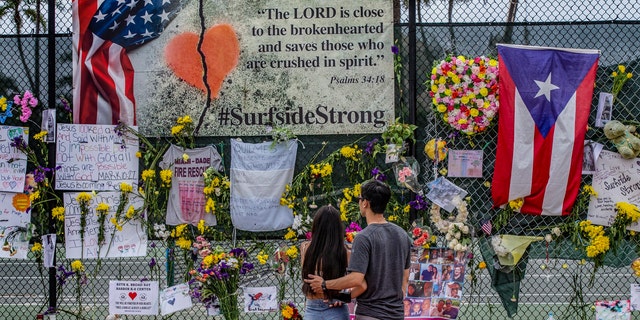 Moments, personal items and flowers are on display at the Surfside Wall of Hope on Wednesday, July 7, 2021 at Surfside (Fla).  The exhibition will honor those killed during the fall of the Champlain Towers South, a 12-story beachfront in Surfside.  .  (Al Diaz / Miami Herald via AP)