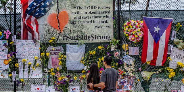 Momentos, personal items and flowers are displayed at the Surfside Wall of Hope Memorial on Wednesday, July 7, 2021, in Surfside, Fla. The display honors those who died during the collapse of the 12-story oceanfront condo, Champlain Towers South in Surfside. (Al Diaz/Miami Herald via AP)