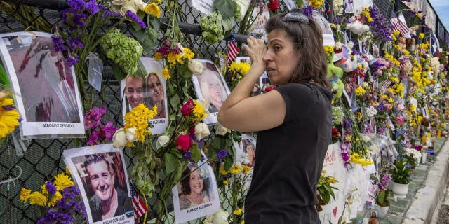 Gini Gonte visits Surfside Wall of Hope & Memorial on July 7, 2021 to honor friends who lost their lives after the collapse of Champlain Towers South in Surfside, Florida. (Al Diaz / Miami Herald via AP)