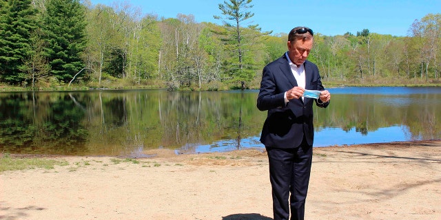 FILE - This photo from May 21, 2020, shows Connecticut Gov. Ned Lamont as he prepares to put on a face mask before his daily COVID-19 briefing, Gay City State Park in Hebron, Conn. Lamont's office say they will no longer provide daily updates on the number of people who have died in the state from COVID-19-related causes. (AP Photo/Pat Eaton-Robb, File)