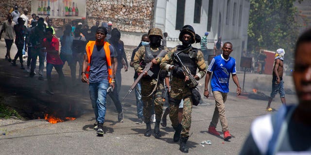 Police walk among protesters during a protest against the assassination of Haitian President Jovenel Moïse near the police station of Petion Ville in Port-au-Prince, Haiti, jueves, mes de julio 8, 2021.