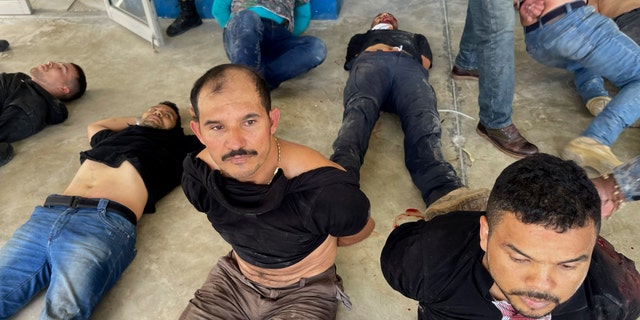 Suspects in the assassination of Haiti's President Jovenel Moise sit on the floor handcuffed after being detained, at the General Direction of the police in Port-au-Prince, Haiti, Thursday, July 8, 2021. A Haitian judge involved in the murder investigation said that President Moise was shot a dozen times and his office and bedroom were ransacked. (AP Photo/Jean Marc Hervé Abélard)