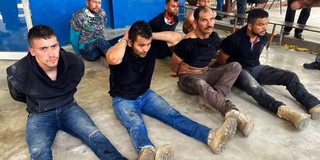 Suspects in the assassination of Haiti's President Jovenel Moise sit on the floor handcuffed after being detained, at the General Direction of the police in Port-au-Prince, Haiti, jueves, mes de julio 8, 2021.