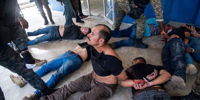 Suspects in the assassination of Haiti's President Jovenel Moise sit on the floor after being detained, at the General Direction of the police in Port-au-Prince, Haiti, Thursday, July 8, 2021. A Haitian judge involved in the murder investigation said that President Moise was shot a dozen times and that his office and bedroom were ransacked. (AP Photo/Jean Marc Hervé Abélard)