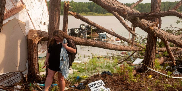 This photo provided by the U.S. Navy, Missy Lattanzie, an RV park resident, searches through her belongings that were destroyed after a tornado touched down Wednesday on Naval Submarine Base Kings Bay, on Thursday, July 8, 2021 in Kings Bay, Ga. Severe weather from Tropical Storm Elsa spurred tornado warnings in Delaware and New Jersey early Friday as the system moved over the mid-Atlantic states and into the northeastern United States.  (Mass Communication 3rd Class Aaron Xavier Saldana/U.S. Navy via AP)