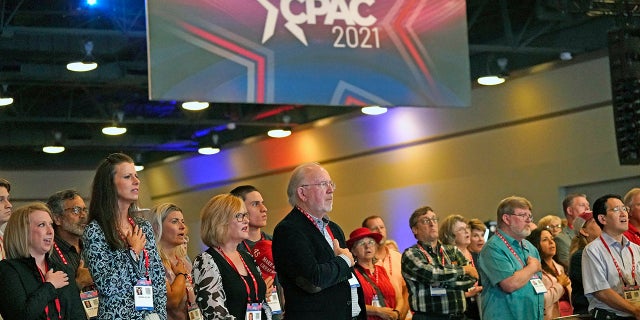 Conservative supporters place their hands over their chest during the national anthem at the opening general session of the Conservative Political Action Conference (CPAC) Friday, July 9, 2021, in Dallas. (AP Photo/LM Otero)