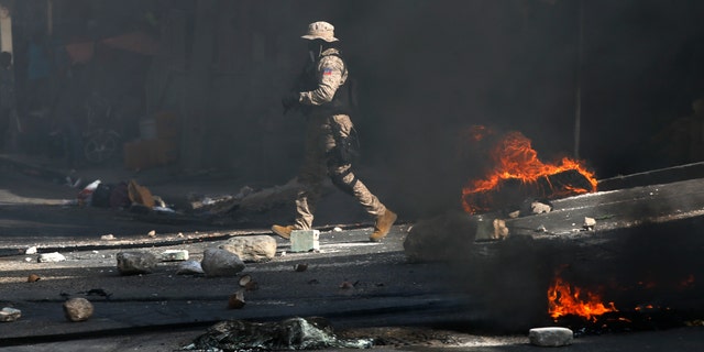 Police work to clear a road blocked by rocks and tires set fire by protesters upset with growing violence in the Lalue neighborhood of Port-au-Prince, Haiti, Wednesday, July 14, 2021. Haitian President Jovenel Moise was assassinated on July 7. (AP Photo/Fernando Llano)