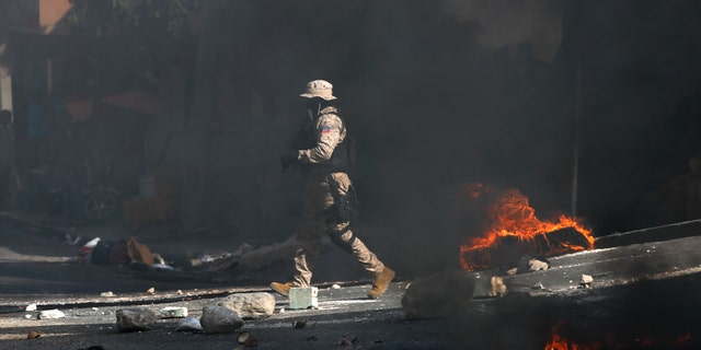 Police work to clear a road blocked by rocks and tires set fire by protesters upset with growing violence in the Lalue neighborhood of Port-au-Prince, Haiti, Wednesday, July 14, 2021. Haitian President Jovenel Moise was assassinated on July 7. (AP Photo/Fernando Llano)