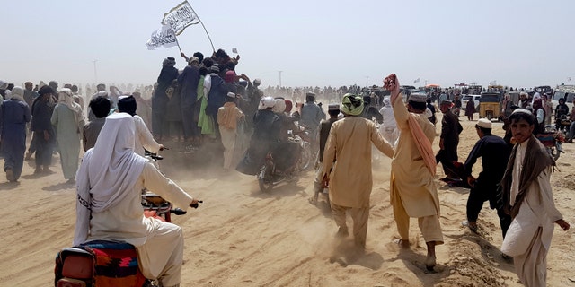 Supporters of the Taliban carry the Taliban's signature white flags in the Afghan-Pakistan border town of Chaman, Pakistan, Wednesday, July 14, 2021. (AP Photo/Tariq Achkzai)