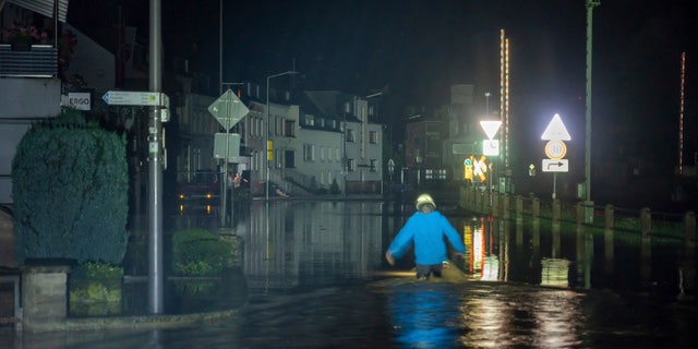 A firefighter wades through a street in Kordel, Germany, which was flooded by the Kyll River, early Thursday, July 15, 2021. Continuous rainfall has flooded numerous villages and cellars in Rhineland-Palatinate, southwestern Germany. (Harald Tittel/dpa ia AP)
