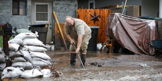 A resident backs up floodwaters as monsoon rains fell on the Museum Fire burn area causing flooding at Paradise Wash east of Flagstaff, Ariz. On Wednesday, July 14, 2021. The threat of flooding lightning will persist until next week, according to the National Weather Service said, although the coverage is more scattered than widespread.  (Jake Bacon / Arizona Daily Sun via AP)