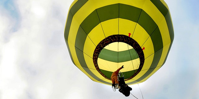 In a harness he created, Brian Boland, of Post Mills, VT, takes off strapped to a hot air balloon with a passenger over Westshire Elementary School in West Fairlee, VT on February 26, 2013 (Associated Press)