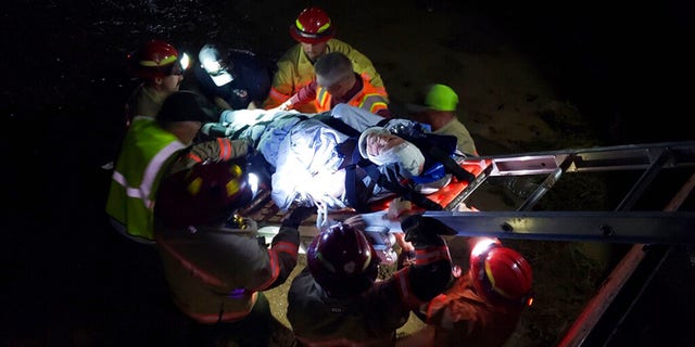 In this photo provided by the Iron County Sheriff's Department, emergency personnel remove an injured train worker from the scene of a derailment near Lund, Utah on Thursday, July 15, 2021. Three workers a freight train were injured when it derailed while crossing water-covered tracks in a remote part of southern Utah Thursday night, authorities said.  The train, which consisted of nearly 100 cars, rolled onto its side after derailing near Lund, about 85 miles from the Nevada border.  (Iron County Sheriff's Department via AP)